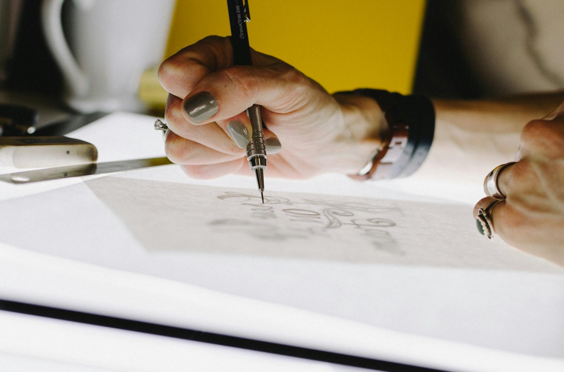 person sketching on a light box