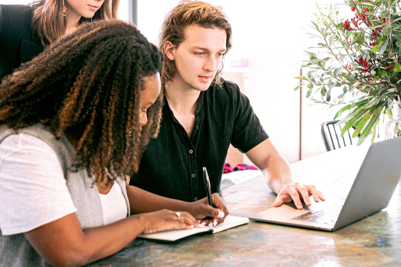 MAn on a computer with a woman taking notes