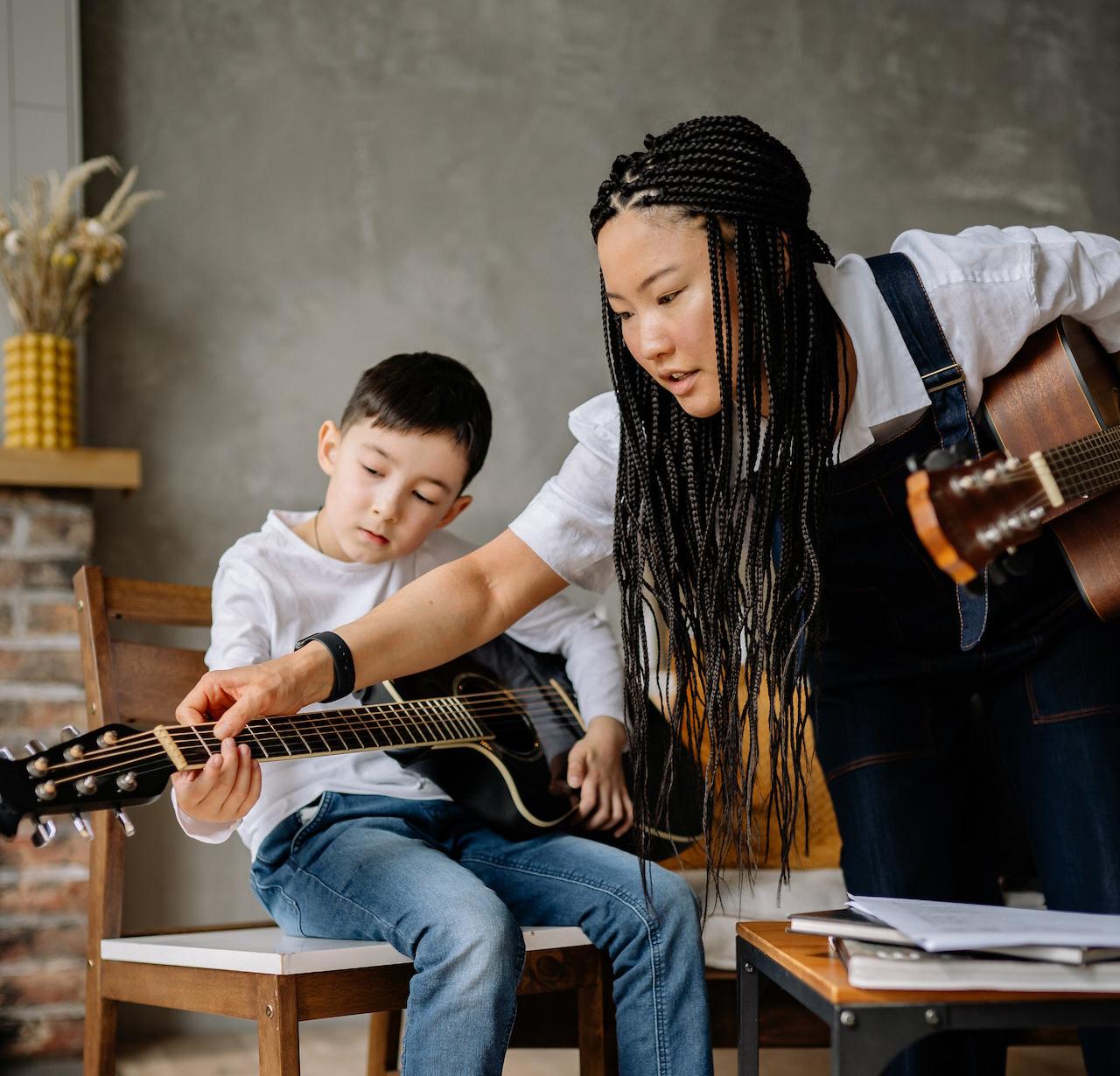 Female music teacher teaching a child the guitar