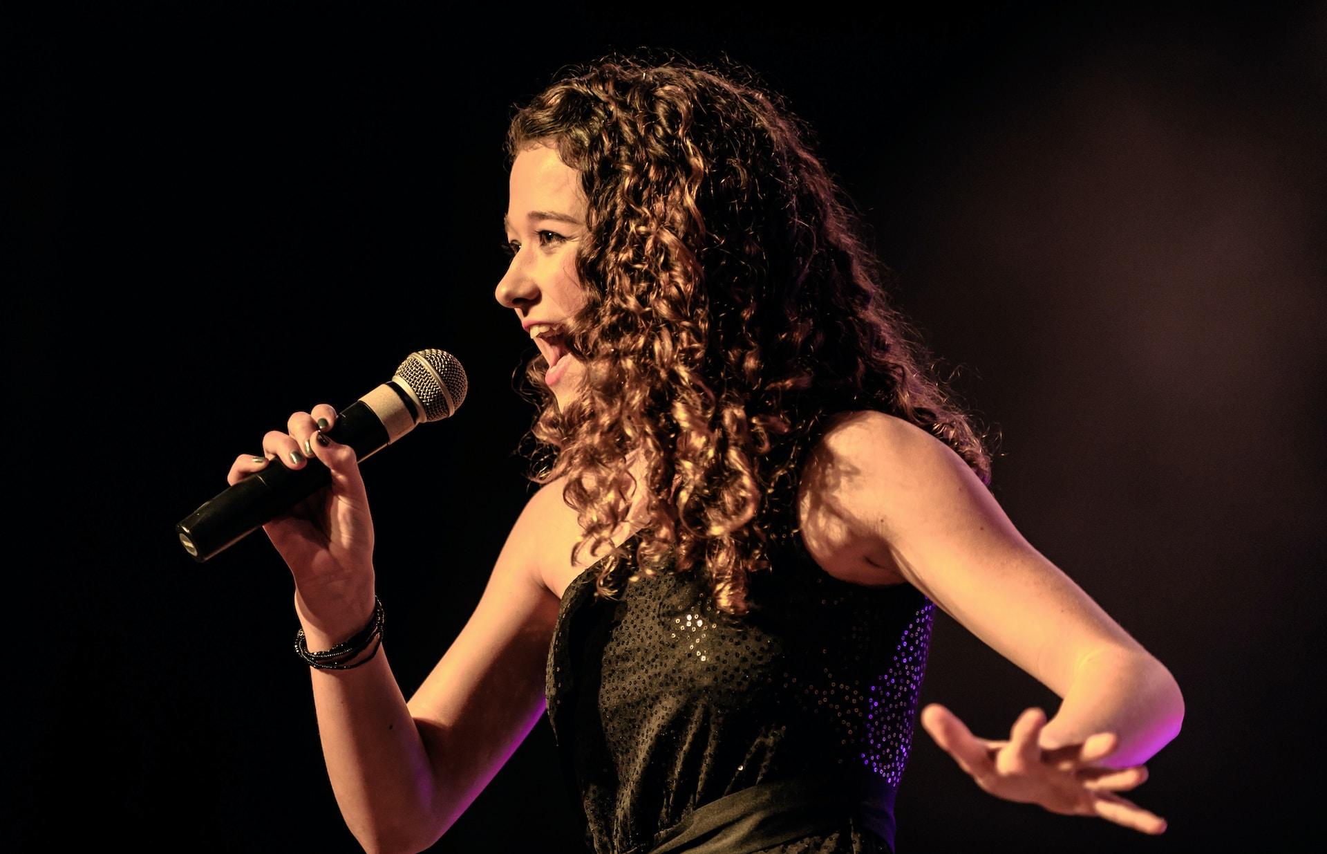 A woman singing on stage dressed in a black dress